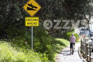 A person riding a bike in The Kerry Saxby walkway next to the Yacht Club Boat Ramp sign next to the Richmond River in Central Ballina, Northern Rivers Region. Limit between River St and Kingsford Smith Dr and next to Richmond River Sailing & Rowing Club.