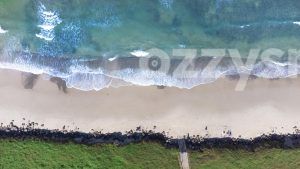 Aerial snap looking directly down on Seven Mile Beach in Lennox Head, showing one of the beach's entry sites as well as the nearby grass and rocks.