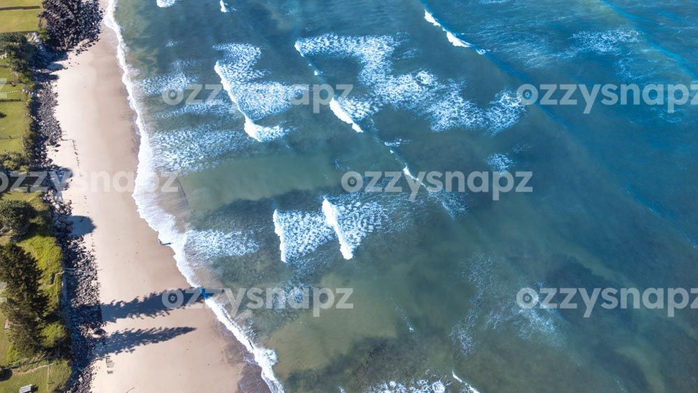 Aerial view of Seven Mile Beach Clear waters from above at Seven Mile Beach in Lennox Head. You can also spot private entries to the beach surrounded by trees and rocks.