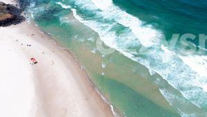 Aerial view looking straight down to East Ballina's Lighthouse Beach north end, where lifeguards and beachgoers can be seen.