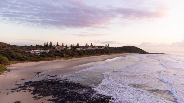 Stunning stock image of Sunrise at Shelly Beach in East Ballina. This drone shot showcases the sparkling sea, rocks, and some of the beautiful waterfront houses.