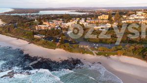 Stock image of Shelly Beach during sunrise, featuring the rockpool, beach-front houses and apartments, and lush greenery.