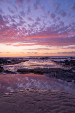 Stunning stock image of sunrise reflections at Shelly Beach rock pool.