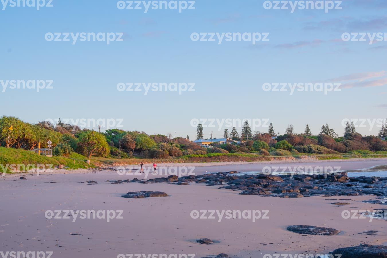 ozzysnapz_221341_low Shelly Beach during sunrise with two women walking among lush greenery and rocks.