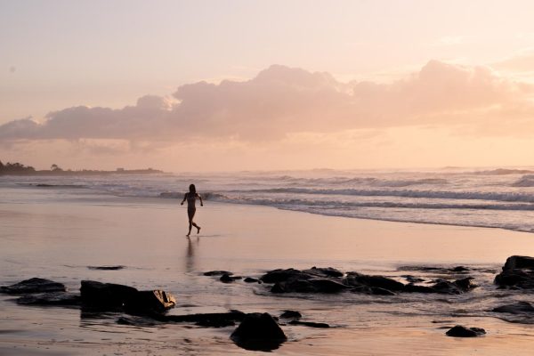 Download this stunning high-contrast lifestyle stock image of a woman running out of the water at Shelly Beach during sunrise.