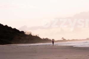 Serene digital stock image of a person jogging on Shelly Beach at sunrise with beautiful bushland in the background.
