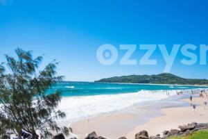 Stunning stock photo of the Main Beach in Byron Bay, with the iconic Cape Byron Lighthouse in the background.